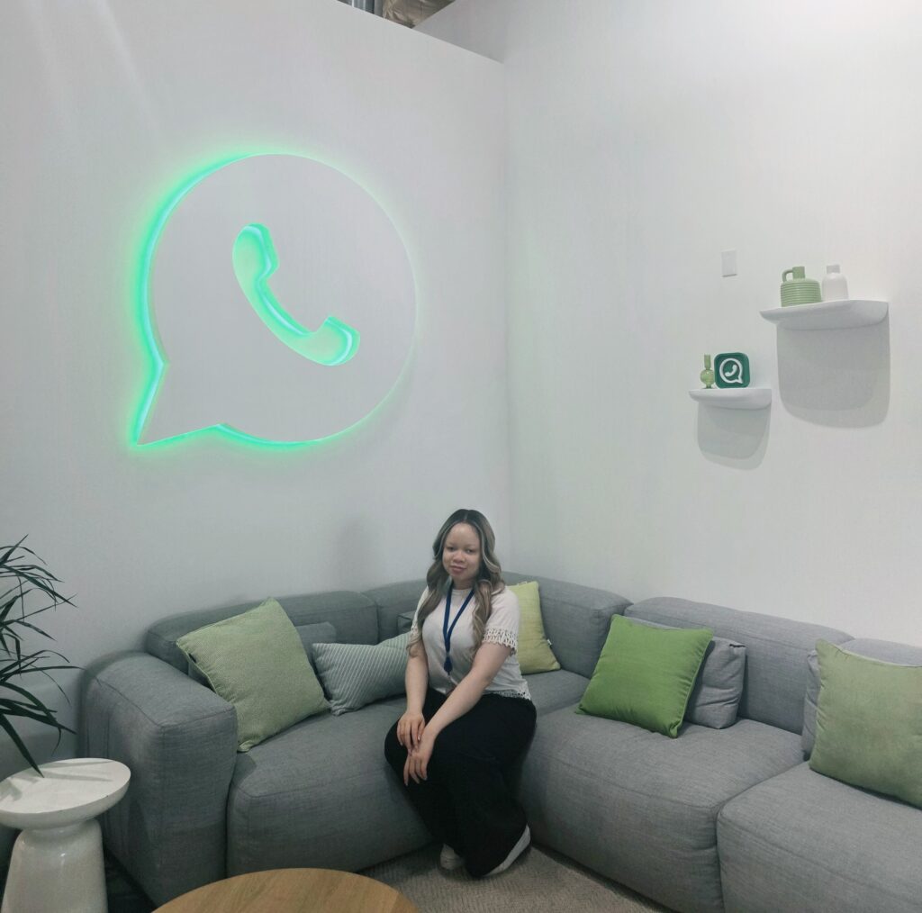 MTSU Student Christabel ObiNwosu sitting in front of the What's App? logo